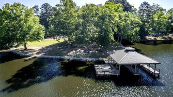 A lakeside property with a dock, a covered pavilion, and a grassy area with trees.