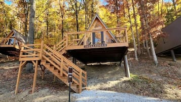 A wooden cabin with a staircase, labeled 'SHENDOAH,' surrounded by autumn trees.