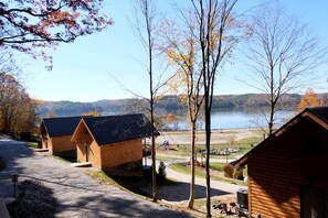 A row of log cabins with a view of a lake and forest.