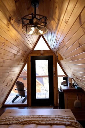 A cozy attic bedroom with a sloped ceiling, a bed, a desk, and a chair.