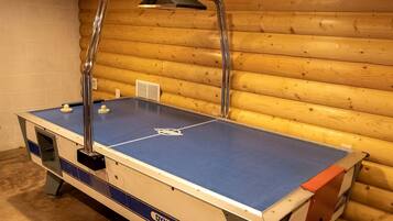 A foosball table in a room with wooden walls and a white brick wall.