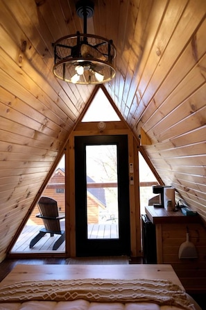 A cozy attic bedroom with a sloped ceiling, a bed, a desk, and a chair. - Lovely Rural Cabin Nestled Among Nature by Tappan Lake in Ohio (Deersville)