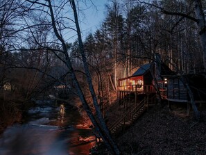 Uma cabana com um deck de madeira e um rio ao fundo.