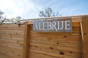 A wooden structure with a metal sign reading 'ALEBRIJEE.'