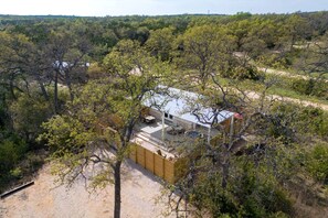 A house surrounded by trees, with a gravel driveway and a visible patio area.