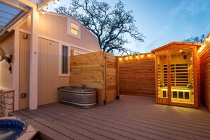 A wooden deck with a hot tub, a sauna, and a wooden fence.
