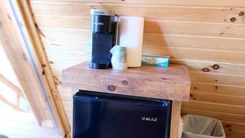 A compact kitchen area with a black U-MAX refrigerator, a coffee maker, and a trash bin.