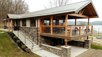 Een lodge met een gevel van natuursteen, een houten terras en een zitgedeelte buiten.