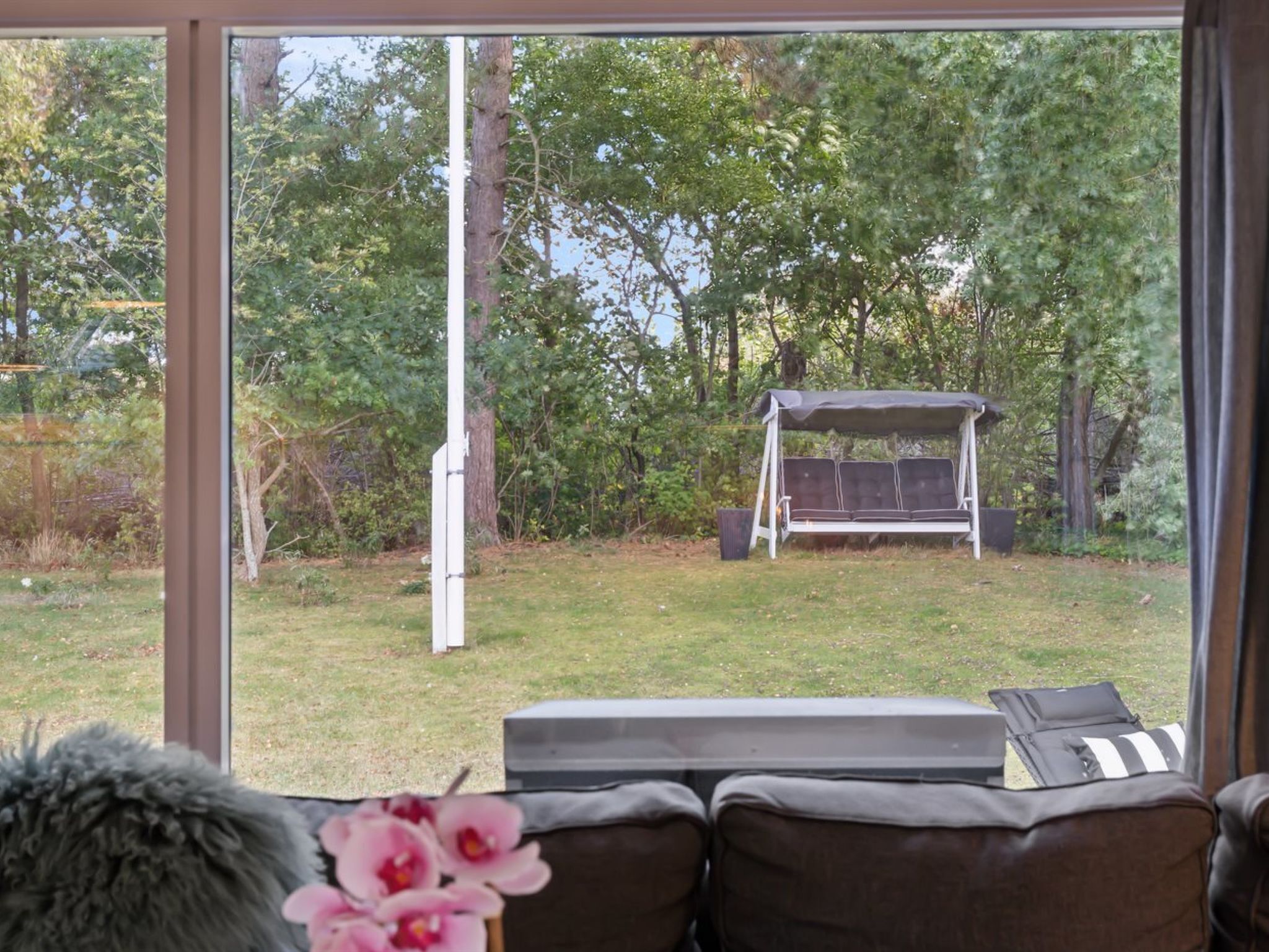 A room with a large window offering a view of a backyard with a swing set and a lawn.