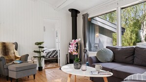 A modern living room with a grey sofa, a small round table, and a chair. There is a bed with a checkered blanket in the background. - "Baarde" - 1.2km from the sea by Interhome (Vejby)