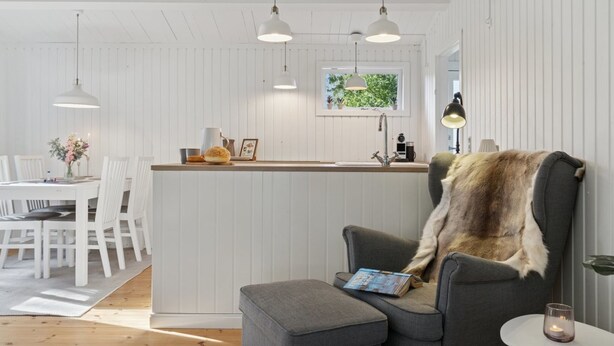 A modern kitchen with white cabinetry, pendant lighting, a central island, and a cozy seating area with a fur throw. - "Baarde" - 1.2km from the sea by Interhome (Vejby)