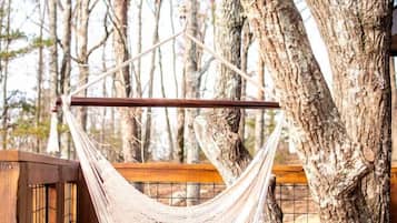 A hammock suspended between trees on a wooden deck.