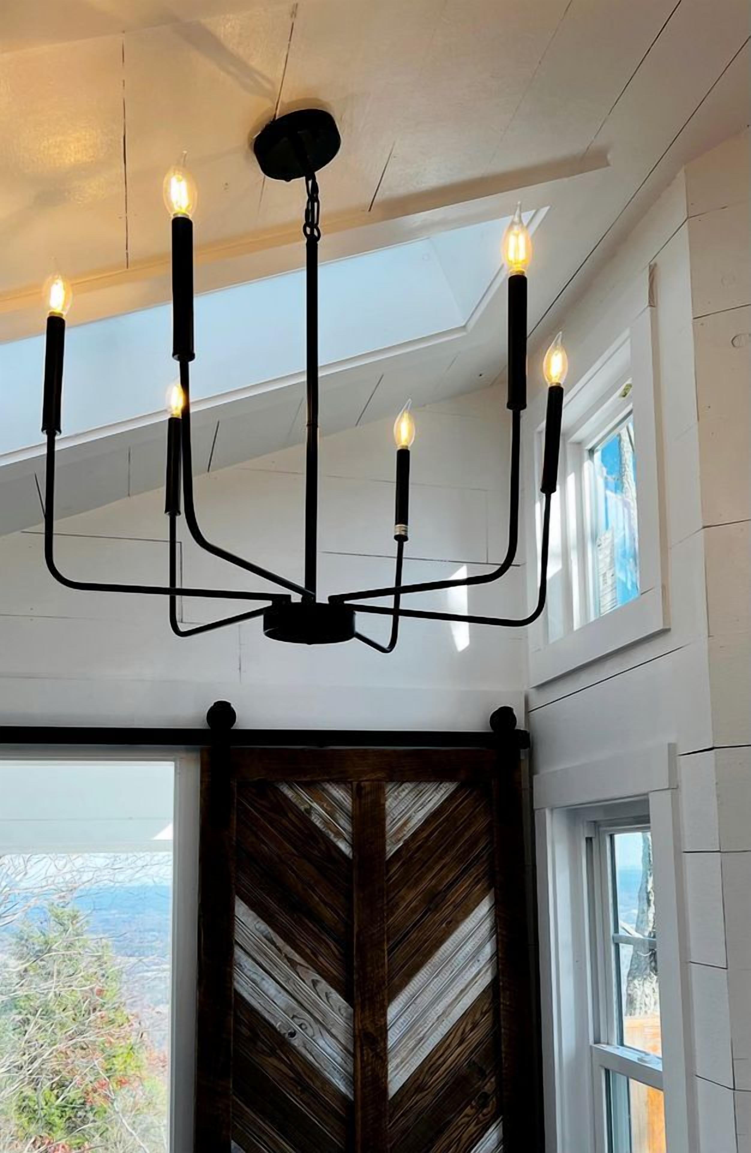 A chandelier with multiple light fixtures, a wooden wall panel, and a window with a view.