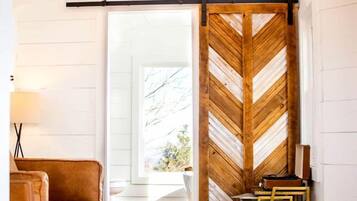 A room with a wooden herringbone wall, a leather sofa, a white rug, and a chandelier.