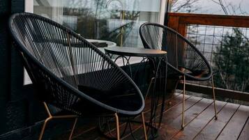 A wooden deck with two black wire-framed chairs and a small table.