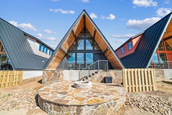 A modern building with a triangular roof, large windows, and a stone patio.
