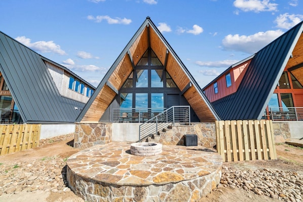 A modern building with a triangular roof, large windows, and a stone patio.