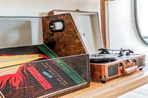 Un tourne-disque ancien, posé sur une surface en bois, avec un haut-parleur recouvert d’une grille et un livre à proximité.