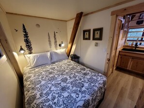 Un dormitorio con cama, mesita de noche, lámpara y armario de madera.