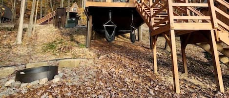 Una cabaña de madera con balcón, rodeada de árboles y hojas otoñales.