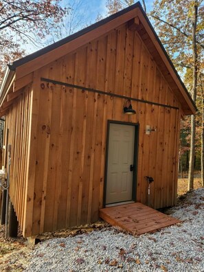 A wooden shed with a door and a small porch.