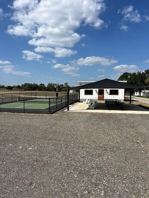Un bâtiment avec un toit noir, un terrain de basketball et un espace pique-nique.