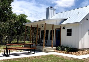A white building with a metal roof, a wooden bench, and a concrete staircase leading to a door. - Charming Cabin for Glamping Vacations in Wimberley, Texas (Wimberley)