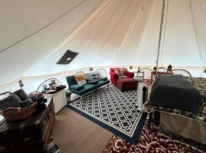 A tent with a bed, a sofa, a red chair, a small table, and a patterned rug. - Magical Glamping Tent in the Woods near Stone Mountain State Park, North Carolina (Wilkes County)