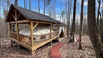 Une cabane en bois dotée d’un espace de couchage abrité, d’un chemin rouge et d’un hamac.