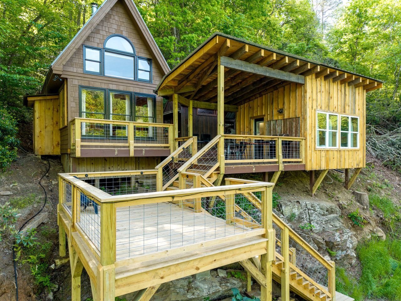 A wooden cabin with a balcony and a deck, surrounded by trees.
