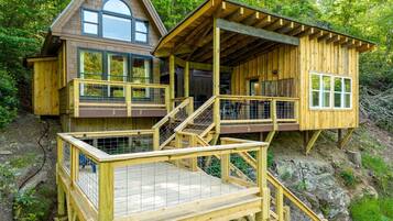 Eine Holzhütte mit Balkon und Terrasse, umgeben von Bäumen.