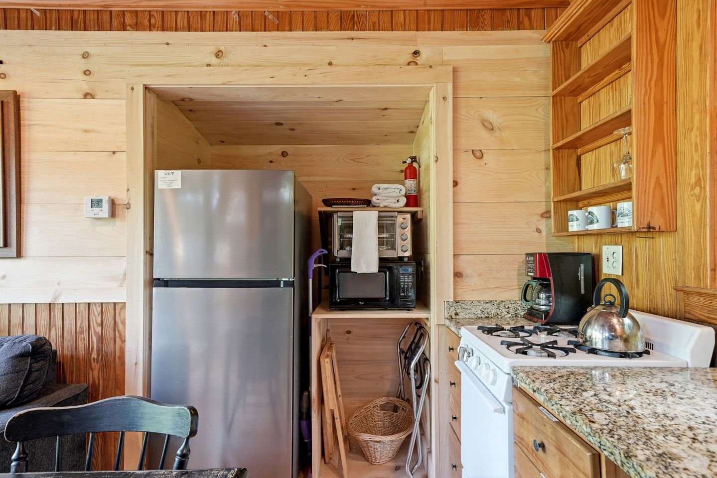 A compact kitchen with a refrigerator, microwave, stove, and wooden cabinets.