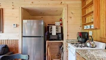 A compact kitchen with a refrigerator, microwave, stove, and wooden cabinets.