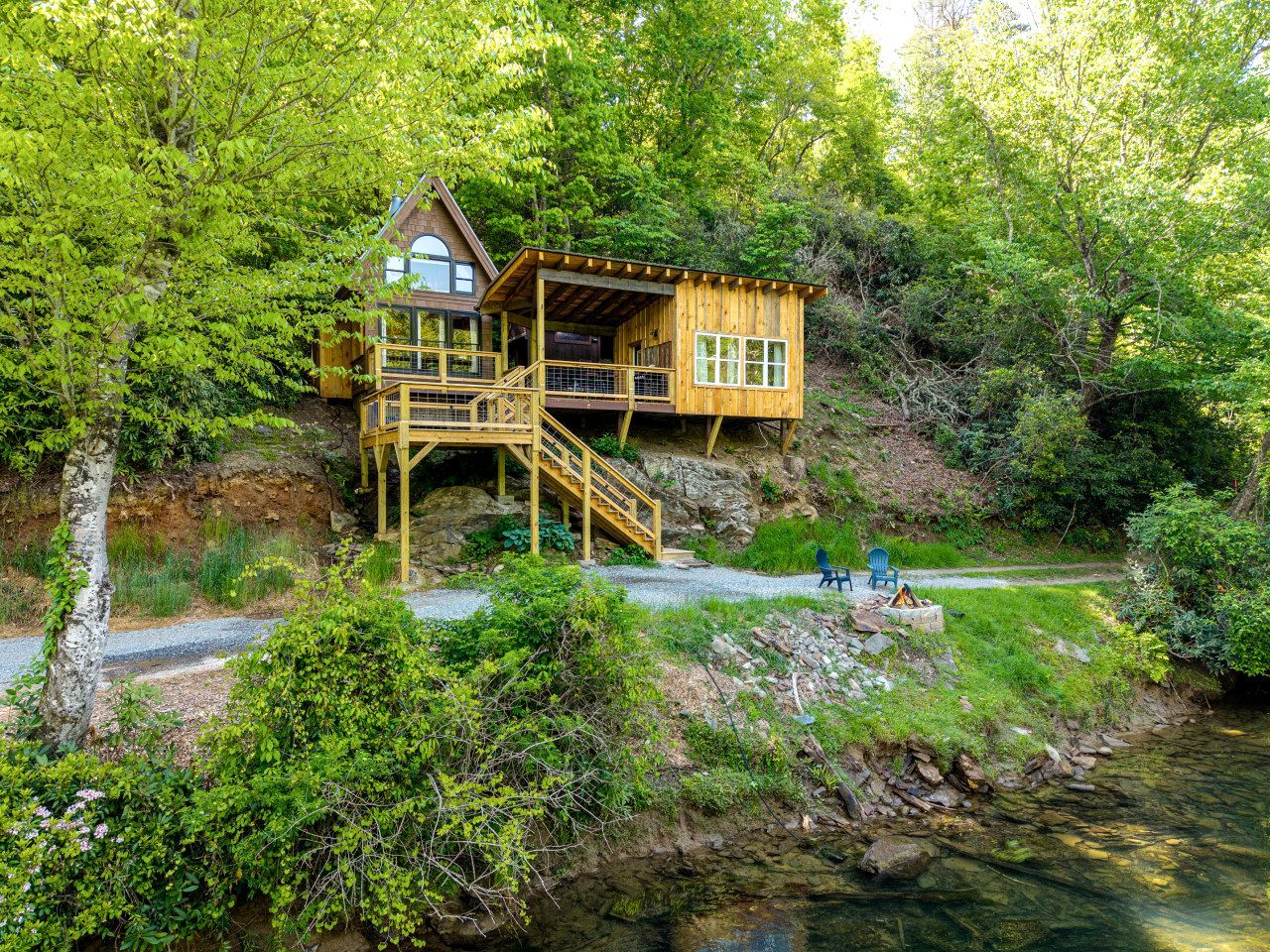 A wooden cabin with a deck, a staircase, and a view of a river.