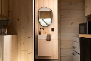 Un intérieur en bois comprenant un évier, un miroir et un four à micro-ondes.