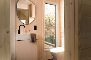 A wooden bathroom with a sink, mirror, and toilet.