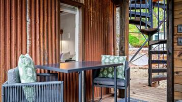 A wooden cabin with a balcony, a table with chairs, and a spiral staircase.