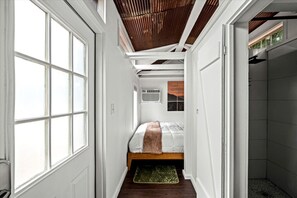 A narrow hallway with a bed, a window, and a door leading to a bathroom. - Beautiful Cabin with Fire Pit in Hayesville, North Carolina (Hayesville)