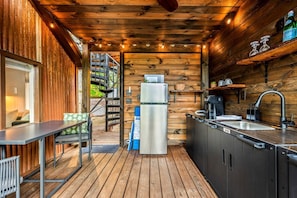 A compact kitchen with a refrigerator, sink, and wooden walls.