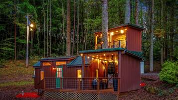 A cabin with a two-story structure, a deck, and a fenced area.