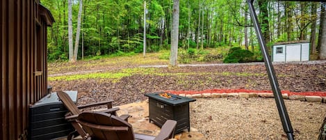 Una terraza de madera con sillas Adirondack, un pozo de fuego y un patio de piedra.