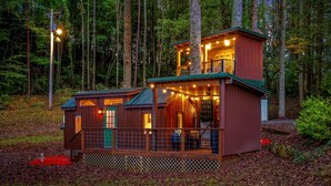 A cabin with a two-story structure, a deck, and a fenced area.
