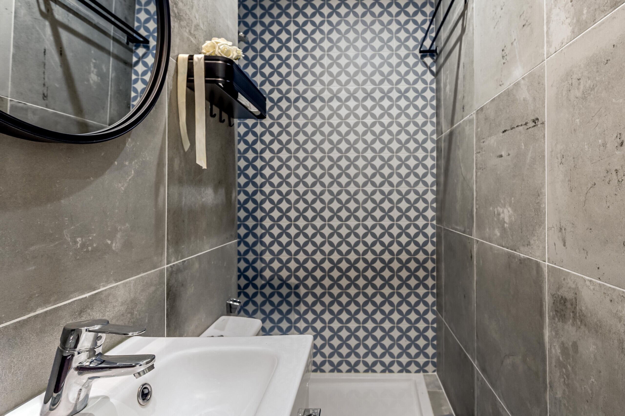 Un baño con lavamanos blanco, un espejo y zona de ducha.