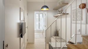 Ein modernes Interieur mit Treppe, Flachbildfernseher und Pendelleuchte.