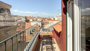 Ein Balkon mit Tisch und Stühlen mit Blick auf eine Stadtlandschaft mit roten Dächern.