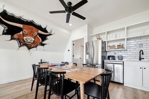 A modern kitchen with white cabinetry, a stainless steel refrigerator, and a ceiling fan. - Chic Spacious A-Frame Ideal for a Relaxing Getaway in Texas (New Braunfels)
