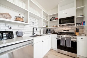 Une cuisine moderne avec des meubles blancs, des appareils en acier inoxydable et un four à micro-ondes placé au-dessus de la cuisinière.