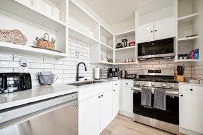A modern kitchen with white cabinetry, stainless steel appliances, and a microwave above the stove.