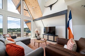 A modern living room with a large TV, comfortable seating, and a view of the outdoors.