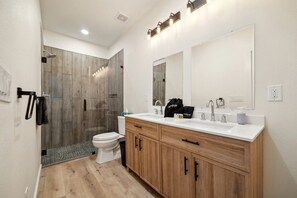 Een moderne badkamer met douche, toilet, wastafel en een grote spiegel.